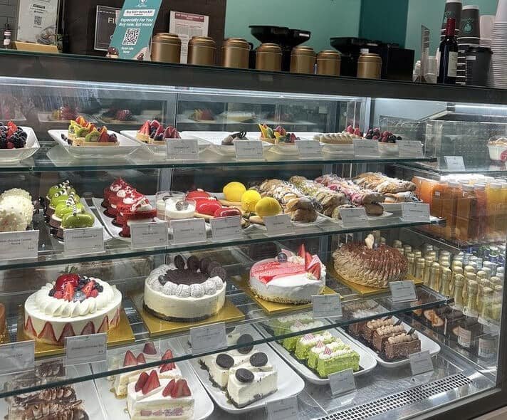 Bakery display case of cakes, key lime pie, Oreo cheese cake, strawberry shortcake, and other desserts
