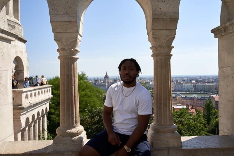 Photo of man sitting down at Fisherman’s Bastion with city view behind him